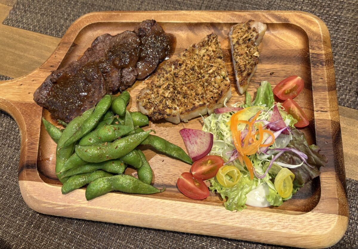 網走「UROKO」の肉料理。スキレットに乗ったボリュームのあるビーフとポークのグリル。付け合わせにポテト、コーン、パプリカ、ブロッコリーが添えられ、食欲をそそる彩り豊かな一皿。
Grilled beef and pork served on a sizzling skillet at "UROKO" in Abashiri. Accompanied by roasted potatoes, corn, bell peppers, and broccoli.