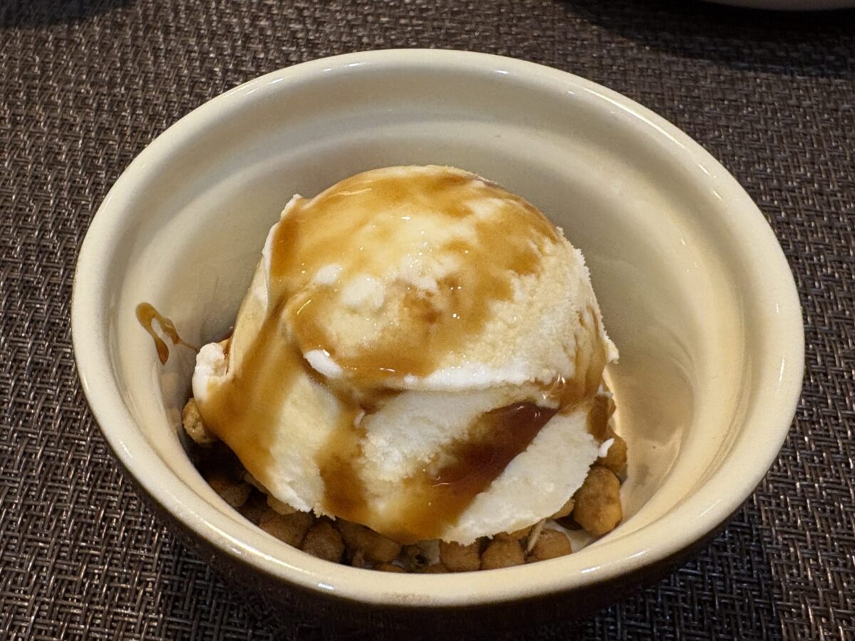 網走「UROKO」のデザート。冷たいバニラアイスクリームに温かいソースをかけて楽しむアフォガートスタイル。シックなグレーの器に盛り付けられ、食後の贅沢なひとときを演出している。
An affogato-style dessert at "UROKO" in Abashiri. Vanilla ice cream served in a stylish gray bowl, with a warm sauce being poured over it.