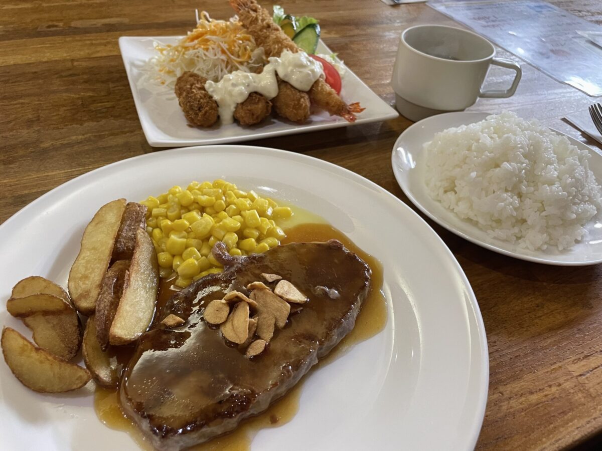 網走「レストラン ホワイトハウス」の人気コンボメニュー。ジューシーな厚切りビーフステーキと、大きなエビフライ、カキフライが一つのお皿に盛られた、ボリューム満点で贅沢な洋食セット。
A hearty combo plate at "Restaurant White House" in Abashiri, featuring a thick beef steak served alongside crispy fried shrimp and oysters.