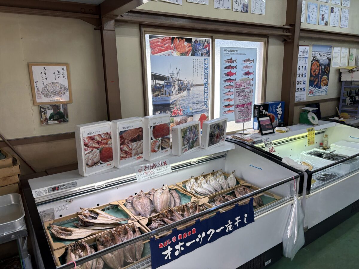 網走「増田水産」の店内に並ぶ自家製の一夜干し。脂の乗ったホッケやニシンなど、オホーツク海で獲れた新鮮な魚を丁寧に干し上げた、網走ならではの豊かな海産物売場の様子。
A display of house-made "Ichiyaboshi" (overnight-dried fish) at Masuda Suisan in Abashiri. The selection includes premium dried atka mackerel and herring, showcasing the authentic seafood culture of the Okhotsk region.