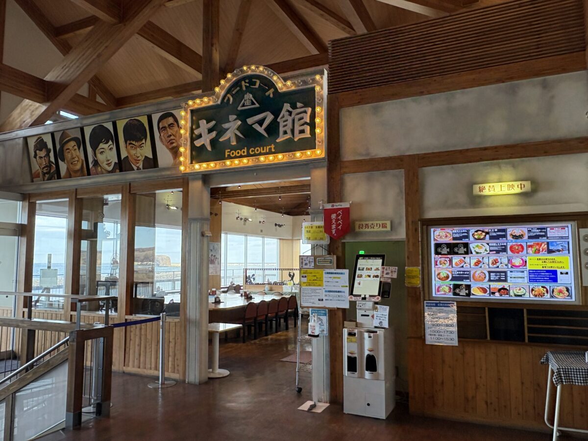 道の駅「流氷街道網走」内にあるレストラン「キネマ館」の入り口。昭和の映画スターたちの肖像画と、電飾で彩られた「キネマ館」のレトロな看板が特徴的。
The entrance to Kinemakan restaurant at the Abashiri Roadside Station, featuring retro portraits of famous Japanese movie stars and a glowing vintage-style theater sign.