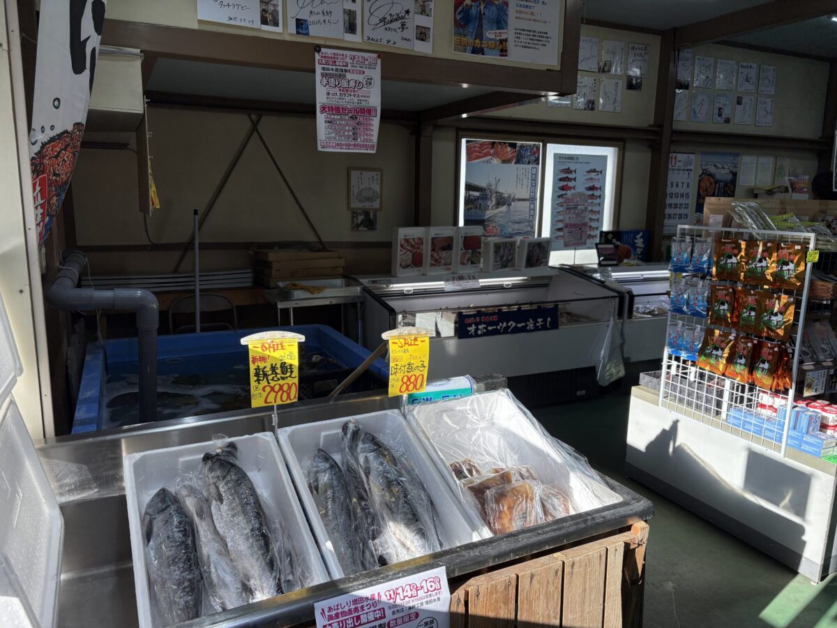 網走「増田水産」の店内に並ぶ新鮮な鮭。新巻鮭や切り身など、オホーツク海で獲れた立派なサケがケース内に整然と陳列されており、網走ならではの活気ある鮮魚店の様子。
A variety of fresh Hokkaido salmon displayed at Masuda Suisan in Abashiri. The image shows whole salted salmon and fillets, representing a typical local seafood market scene in the Okhotsk region.
