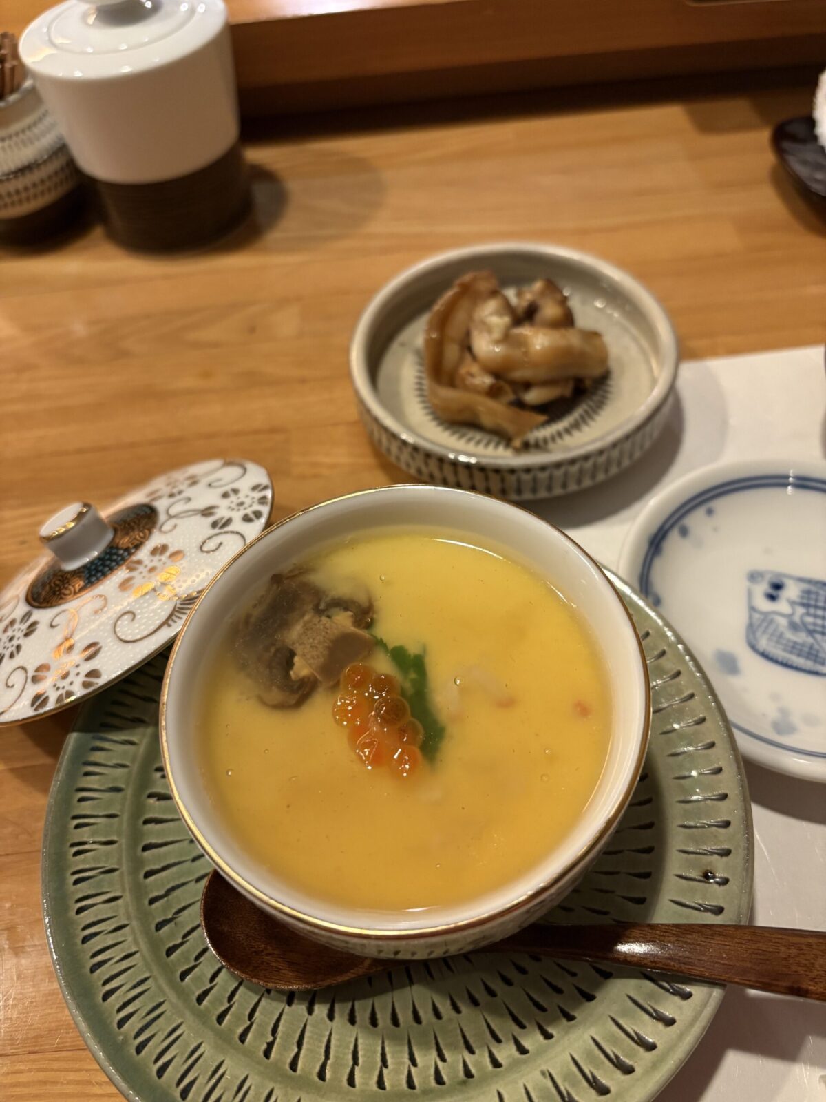 網走「鮨 やまし田」の茶碗蒸し。黄金色の卵液の上に鮮やかな「いくら」がのり、横には食感豊かな「北寄貝のひも」が添えられた、地元の海の幸を堪能できる上品な一皿。
Chawanmushi (Japanese savory egg custard) served at Sushi Yamashita in Abashiri. The dish is topped with shiny salmon roe and accompanied by a side of flavorful Hokkigai (surf clam) mantle, showcasing fresh Okhotsk seafood.