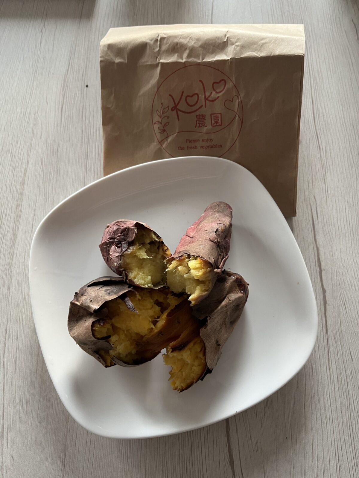 網走流氷まつりの出店で販売されているKOKO農園の焼き芋。白いお皿に乗った熱々の様子
Roasted sweet potatoes from KOKO Farm (KOKO Nouen) at a food stall of the Abashiri Drift Ice Festival, served hot on a white plate.