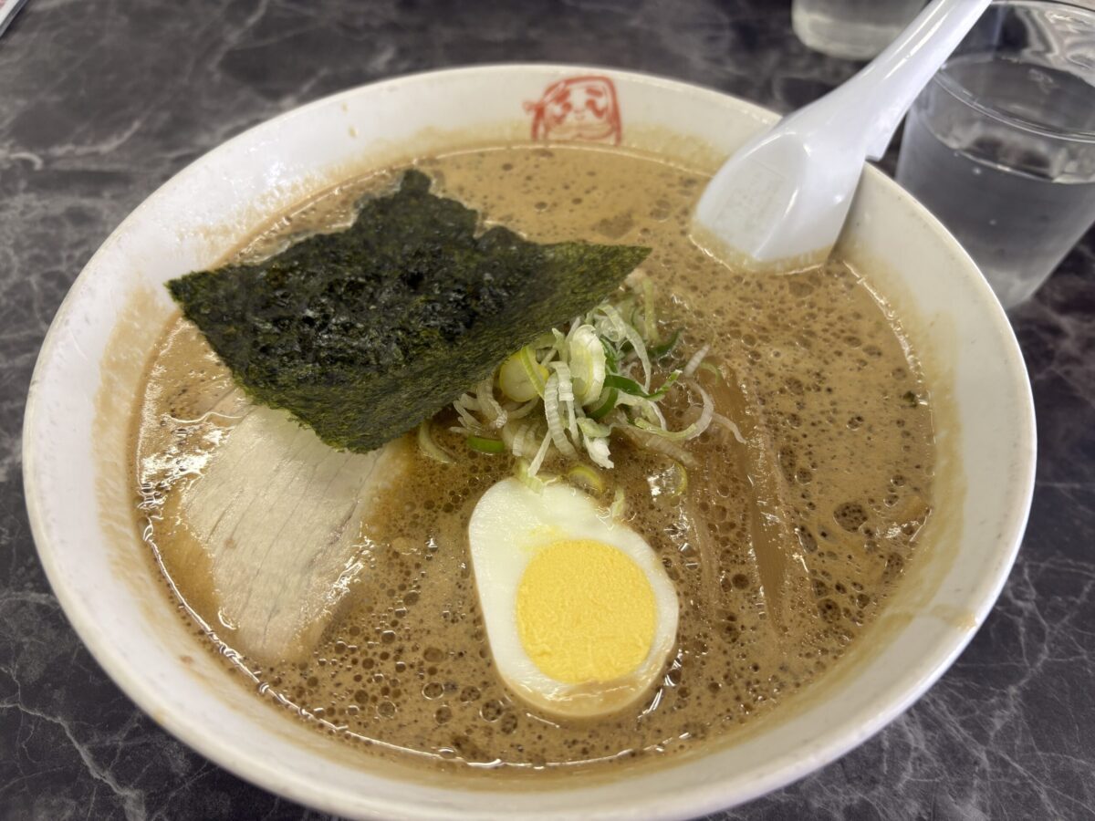 網走「ラーメン だるまや」の名物どろラーメン。濃厚でコクのある特製スープに、チャーミングな煮卵と海苔が添えられた一杯
Abashiri's famous "Doro Ramen" at Darumaya, featuring a signature thick and rich savory broth with toppings.