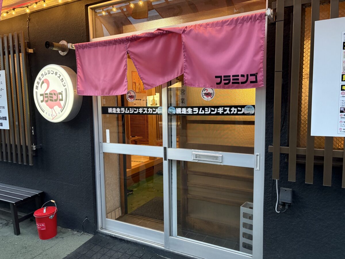 網走「生ラムジンギスカン フラミンゴ」の外観。ピンクの暖簾とフラミンゴの丸看板が目印の、新鮮なラム肉を楽しめる人気店
The vibrant pink entrance and flamingo logo sign of "Raw Lamb Jingisukan Flamingo," a popular local restaurant in Abashiri.