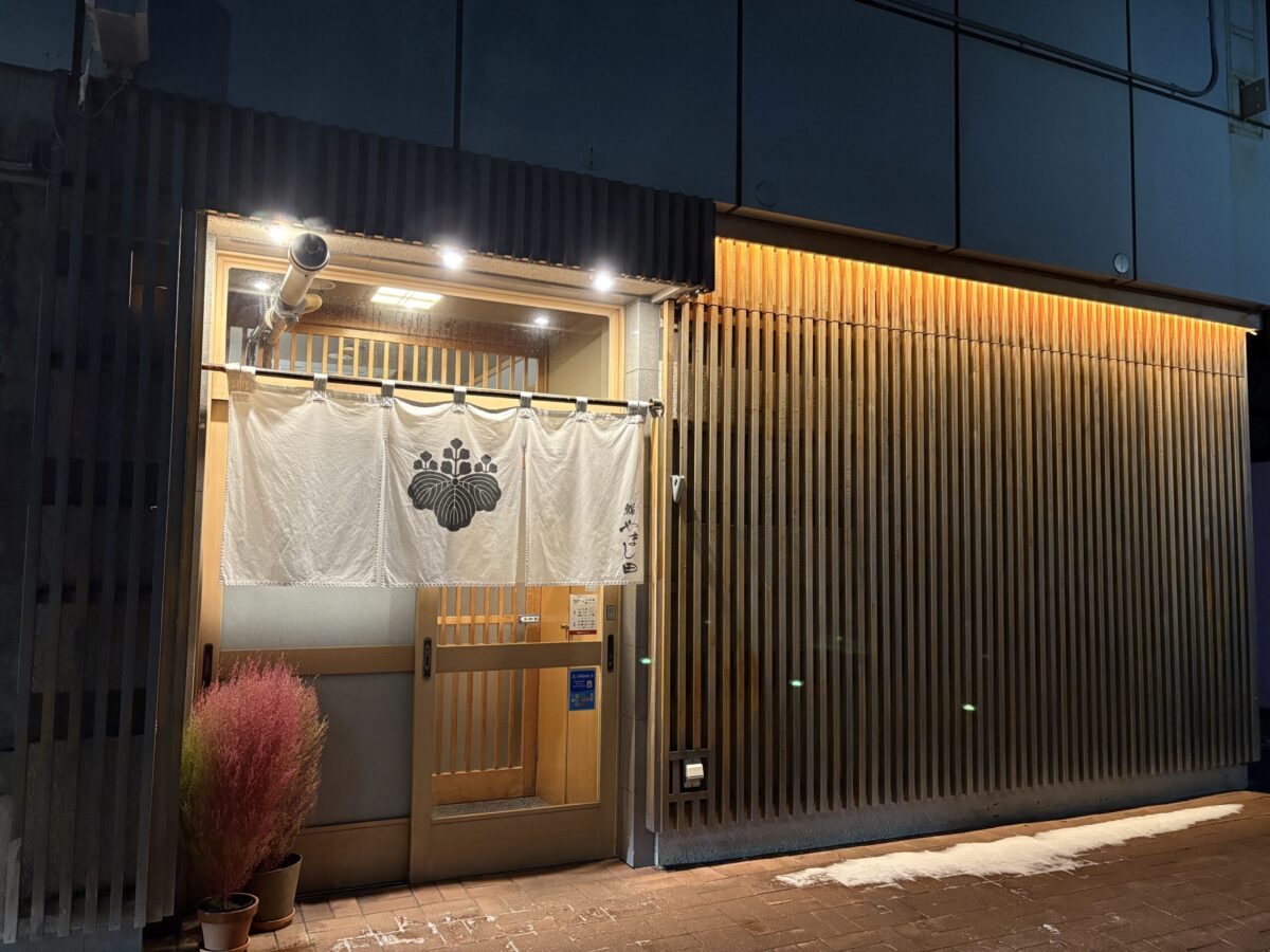 網走「鮨 やまし田」の夜の外観。暖簾(のれん)と木目調の格子が美しい、地元の新鮮な魚介を味わえる高級感のある店構え
The elegant wooden exterior and entrance of Sushi Yamashita in Abashiri at night, a top-rated local sushi restaurant.