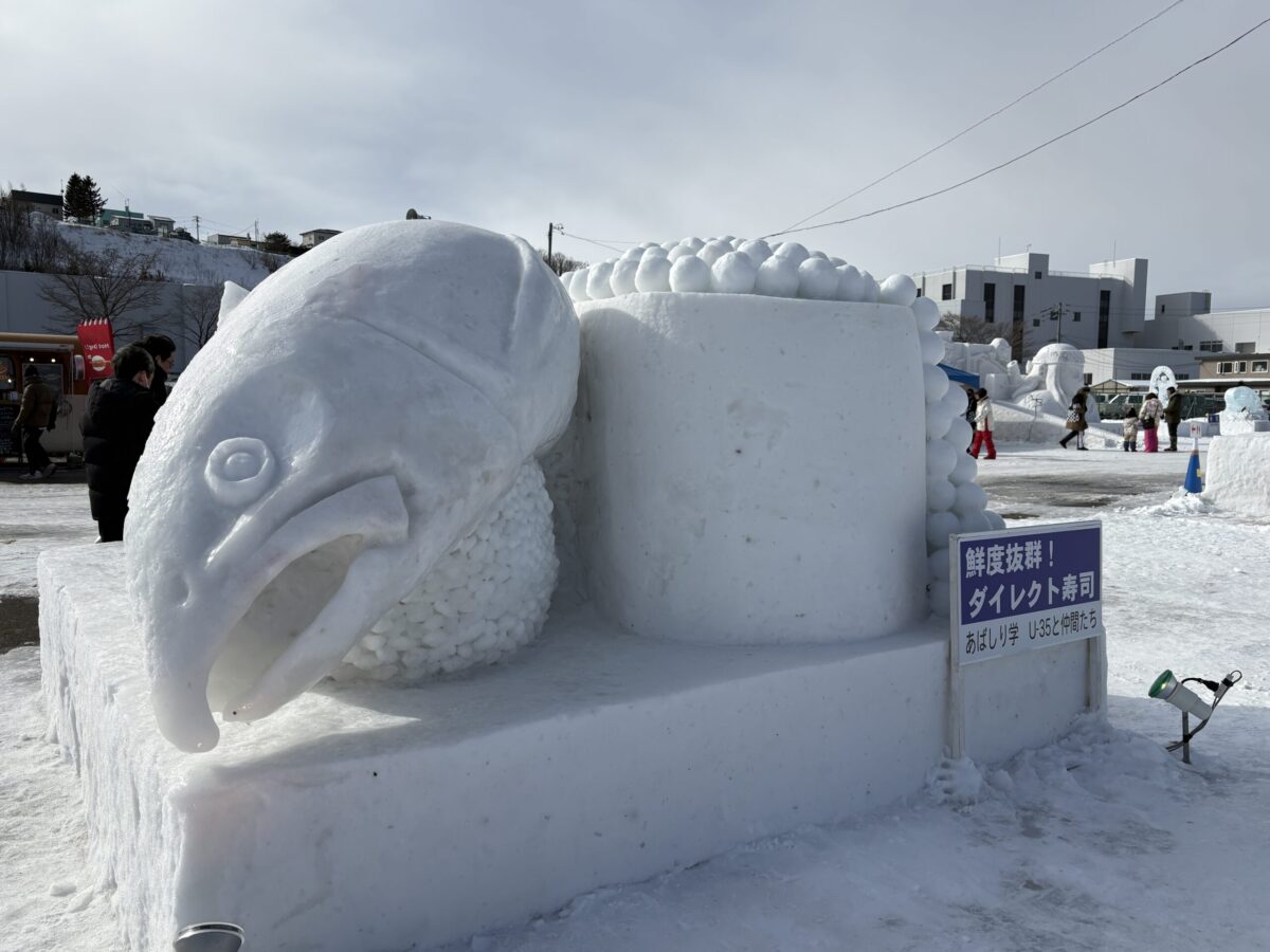 北海道のあばしりオホーツク流氷まつりに登場した、巨大な鮭の握り寿司といくらの軍艦巻きのユニークな雪像。
A unique snow sculpture of giant salmon sushi and ikura (salmon roe) gunkan-maki at the Abashiri Okhotsk Drift Ice Festival in Hokkaido.
