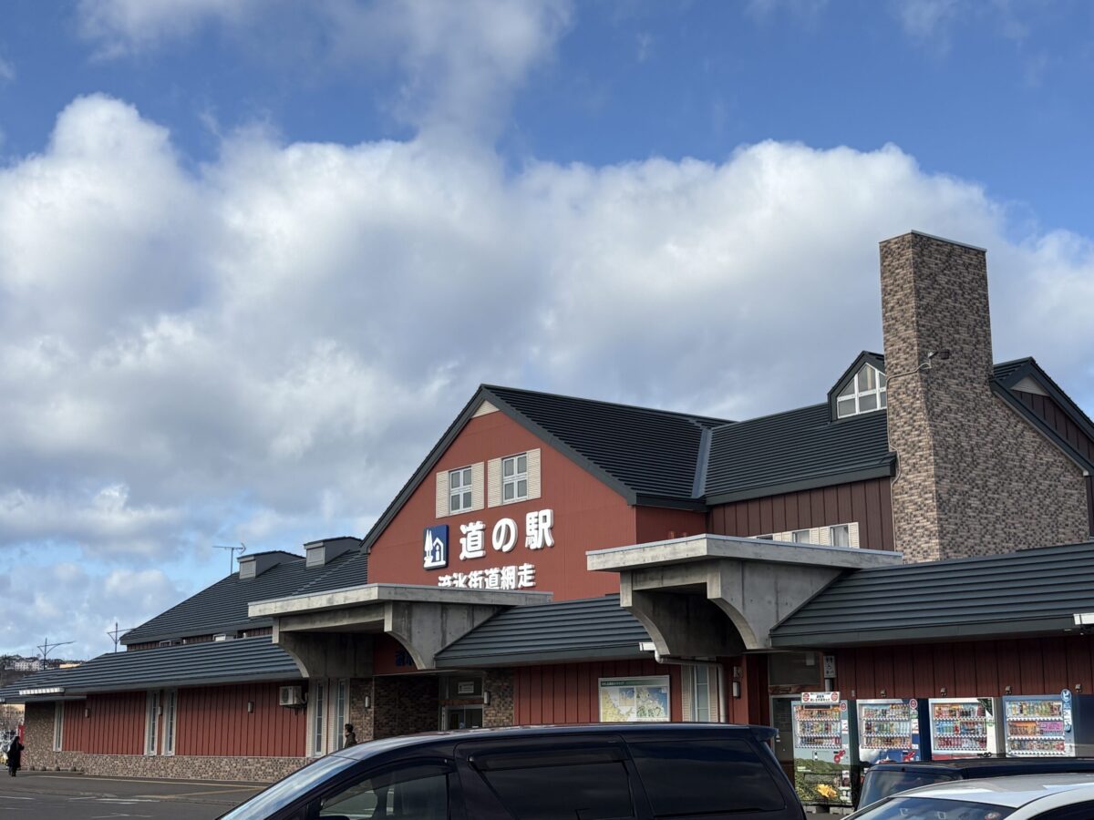 道の駅「流氷街道網走」の外観。青空に映える赤い建物と、冬の観光船「おーろら」の発着拠点となる網走の観光名所 Exterior of the Ryuhyo Kaido Abashiri Roadside Station, a major tourist hub in Abashiri under a clear blue sky.