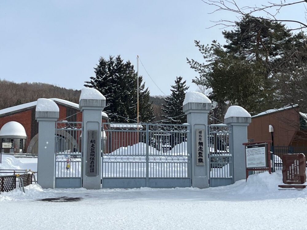 博物館 網走監獄の正門（赤煉瓦門）。雪に覆われた歴史的な重要文化財の建物 The iconic red brick main gate of the Abashiri Prison Museum covered in snow during winter.