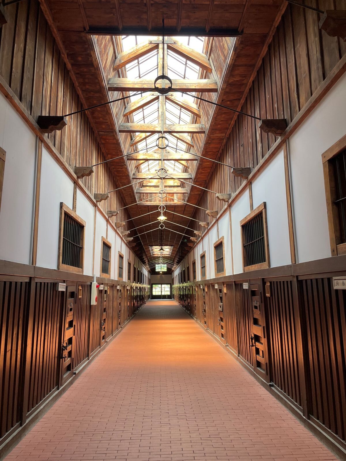 博物館 網走監獄の重要文化財「五翼放射状平屋舎房」。中央見張所から放射状に伸びる木造の独居房廊下
The interior of the Five-Winged Radial Prison House at Abashiri Prison Museum, featuring a long wooden corridor of cells.