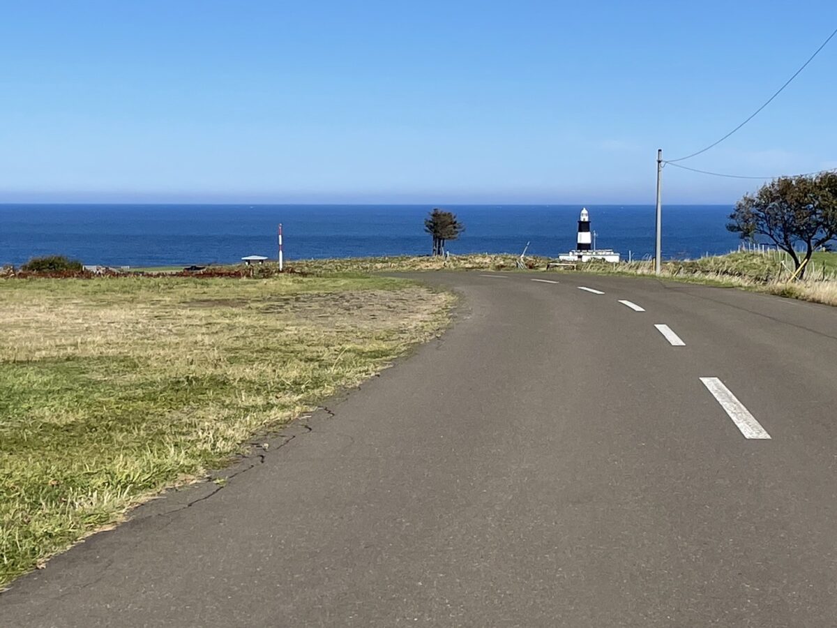 青い海と能取岬灯台へ続く一本道。夏の爽やかな風景