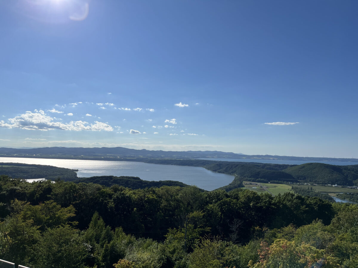 天都山展望台から一望する夏の網走湖。青い空と豊かな緑が広がるパノラマ風景