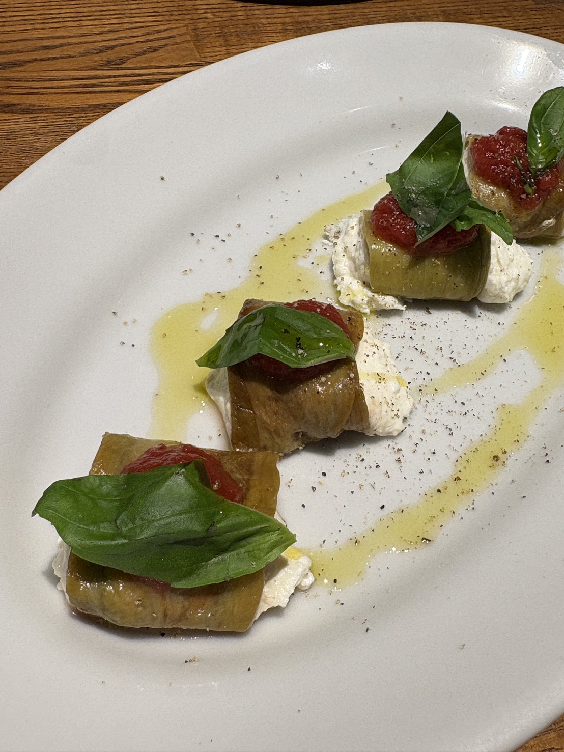 トマトソースとバジルを添えた、茄子とリコッタチーズのおしゃれな前菜
Elegant appetizer of eggplant wrapped with ricotta cheese, topped with tomato sauce and basil at ARUJIS.
