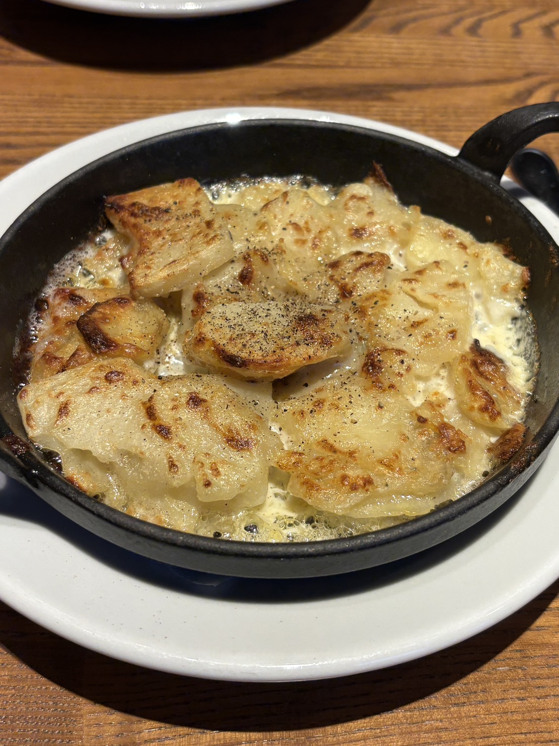 スキレットで熱々に焼き上げられた「ARUJIS」の濃厚ポテトグラタン
Hot potato gratin served in a skillet at HOUSE DINING ARUJIS in Abashiri.