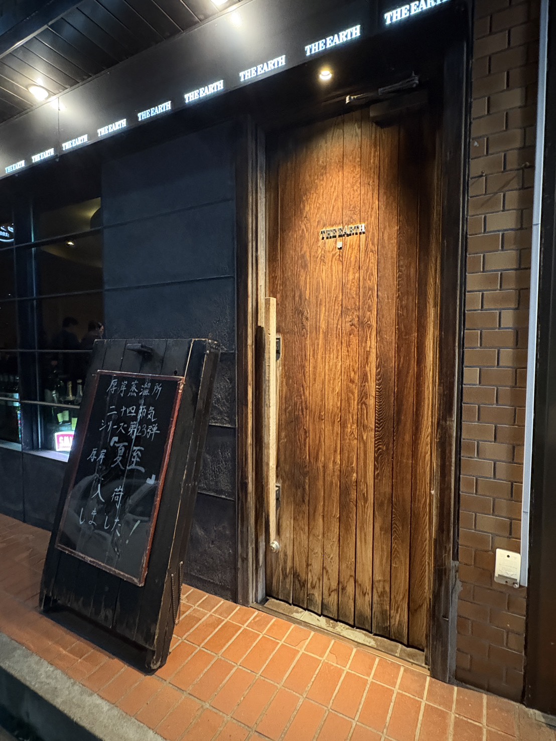 網走の本格派バー「BAR THE EARTH（ジアス）」の重厚な木製の扉と看板の外観
Wooden entrance door and illuminated sign of BAR THE EARTH, a bar in Abashiri, Hokkaido.