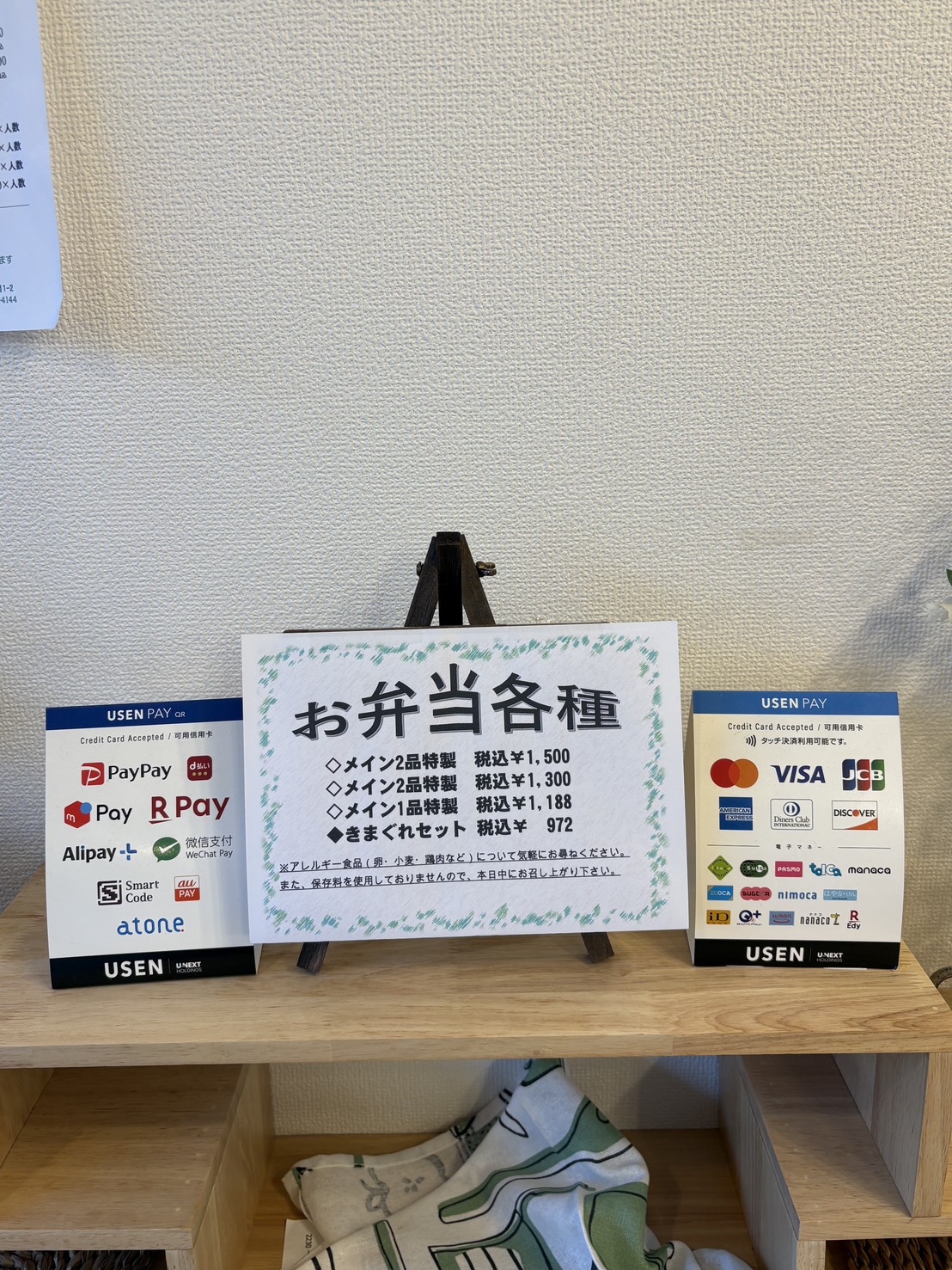 「ja.bitte（ビッテ）」のレジ横にあるクレジットカードやQRコード決済（PayPay、d払い等）の対応一覧
A sign showing accepted cashless payment methods including credit cards and QR codes at ja.bitte.