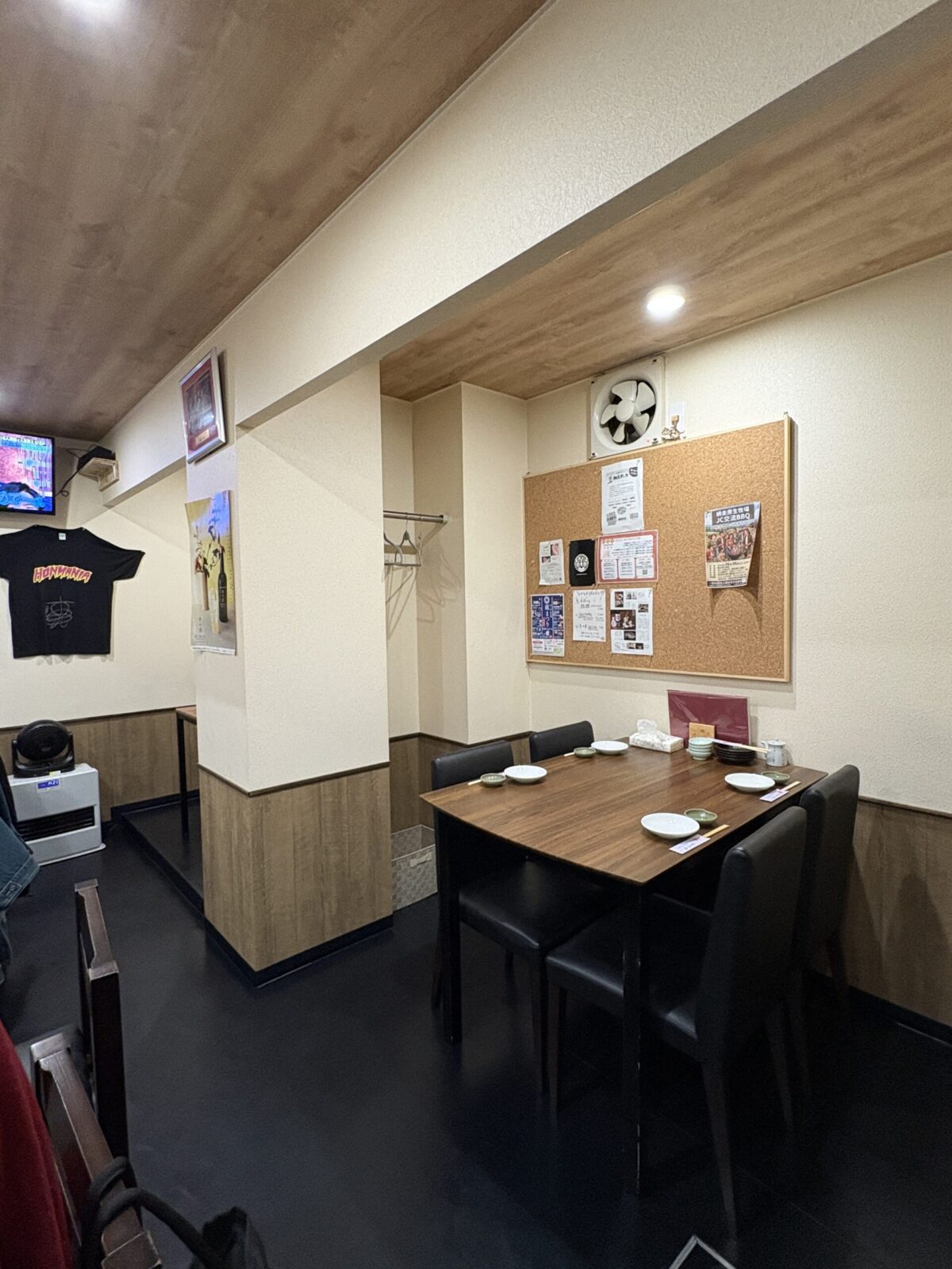 網走「なかの酒場」の店内奥にある、グループ利用に最適な4人掛けの木製テーブル席。壁にはコルクボードの掲示板があり、アットホームで清潔感のある空間
A neat 4-person dining table set next to a cork notice board in a well-lit, clean corner at Nakano Sakaba in Abashiri.