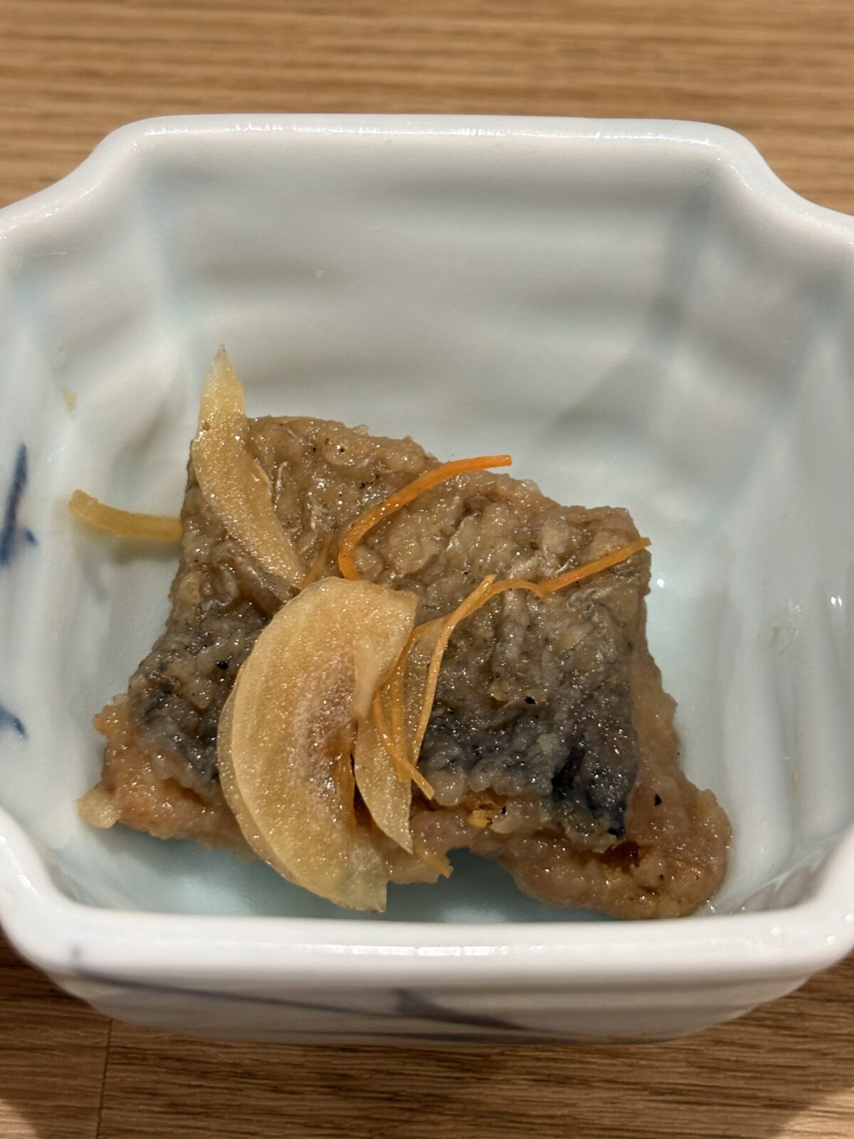 網走「なかの酒場」のお通し、小鉢に美しく盛り付けられたスライス玉ねぎと人参が乗ったニシンの南蛮漬け
Traditional Japanese appetizer of marinated fried herring (Herring Nanbanzuke) topped with sliced onions and carrots in a small bowl at Nakano Sakaba.