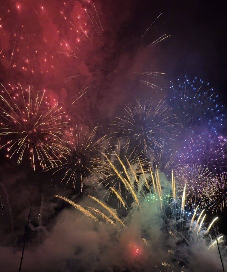 赤や青など色鮮やかな花火を見上げるたくさんの観客と、熱気に包まれたあばしりオホーツク夏まつりの会場 Excited crowds enjoying a spectacular multi-colored fireworks display at the Abashiri Okhotsk Summer Festival