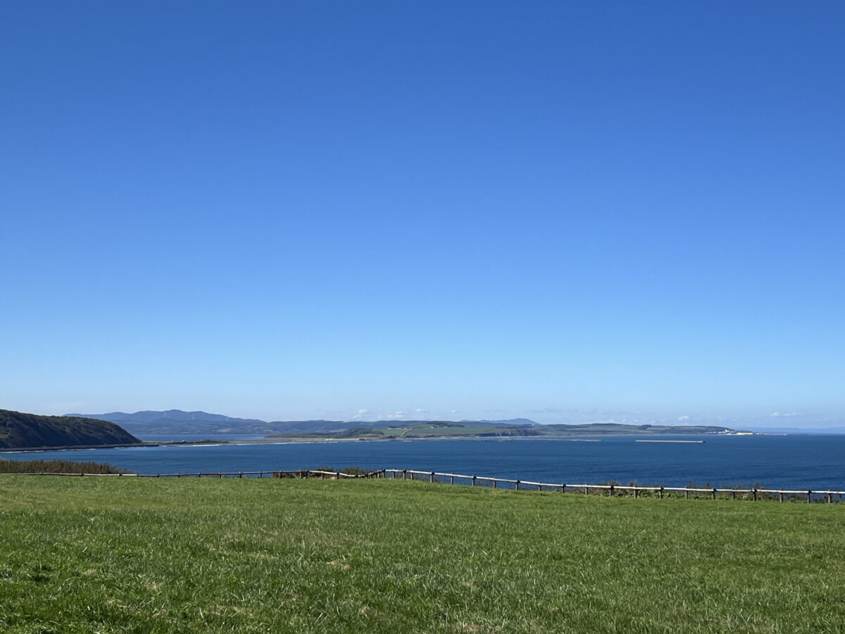 どこまでも続く青空と紺碧のオホーツク海、緑豊かな草原が広がる夏の能取岬の絶景
Breathtaking panoramic view of the deep blue Okhotsk Sea and green grasslands at Cape Notoro in summer