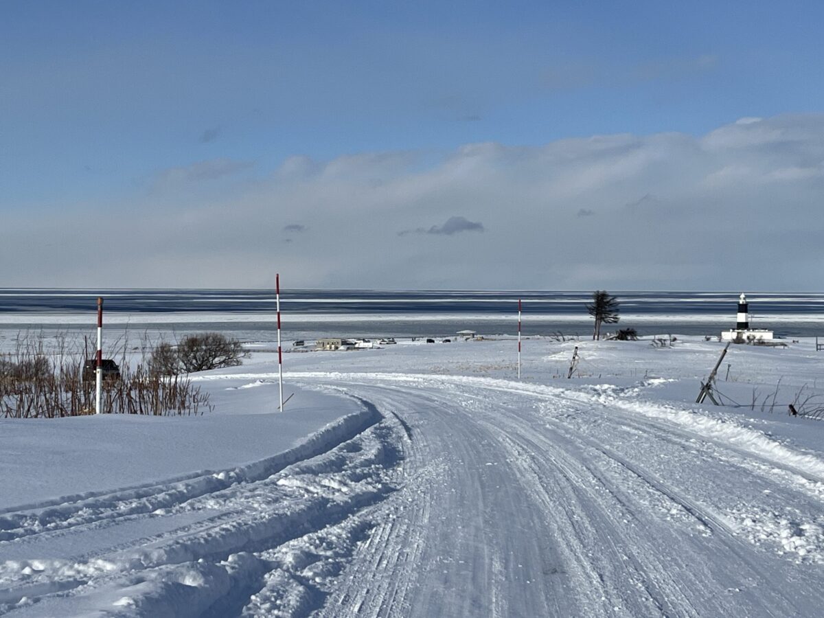 白い雪と赤いポールが目印の、冬の能取岬へと続く静かなドライブロード
A quiet snow-covered road leading to Cape Notoro marked by red and white poles in winter