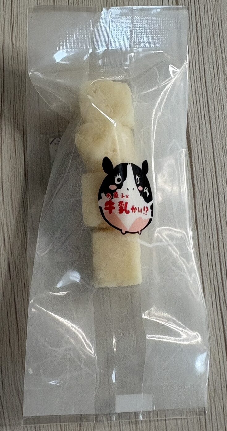 個包装された「お菓子な牛乳かい！？」のミルクグラッセ。やわらかく濃厚な網走生乳の手作り菓子。
Individually wrapped piece of "Okashina Gyunyu-kai!?" milk glace, showing the soft texture of handcrafted milk candy.
