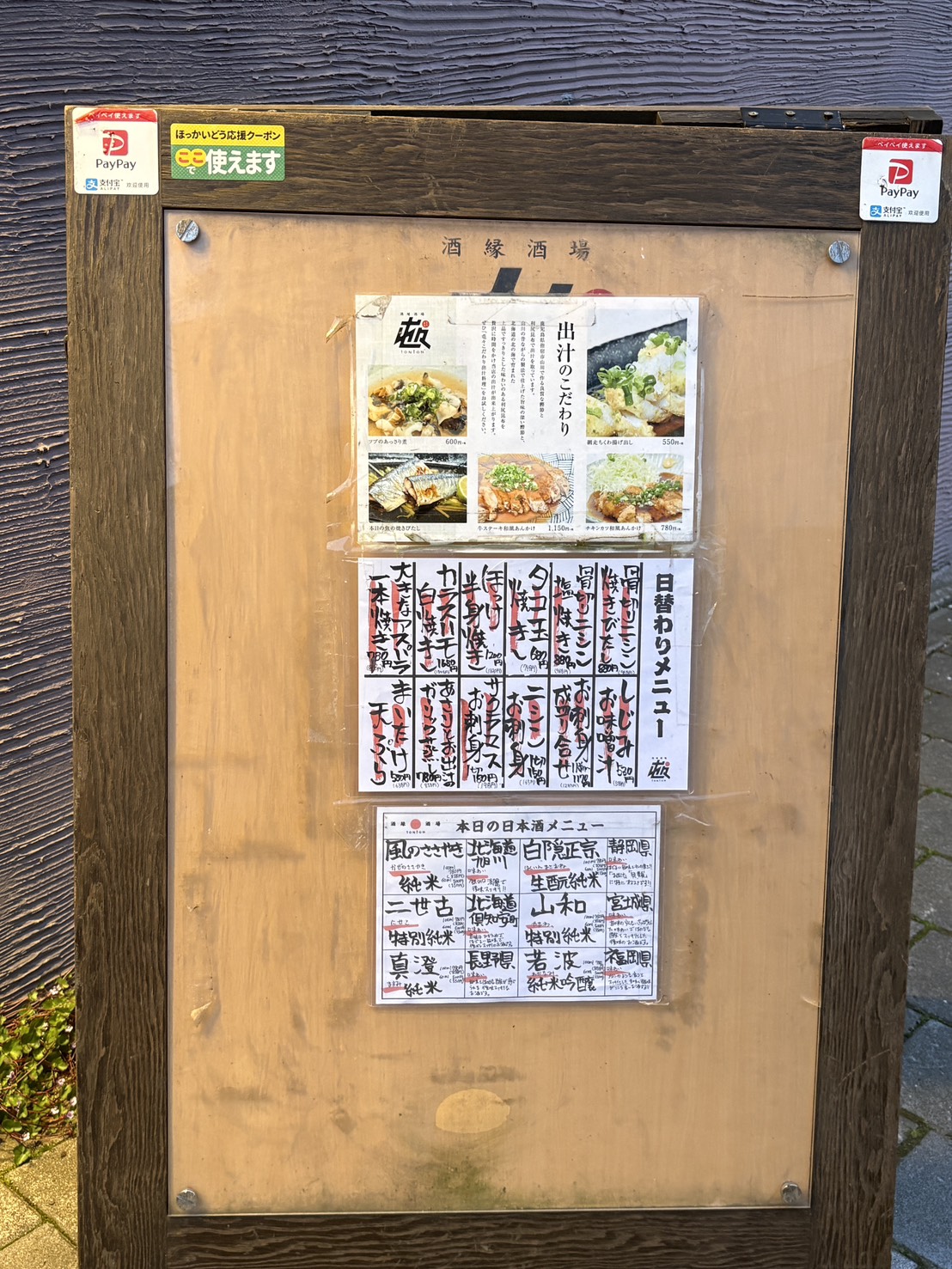 居酒屋「屯屯(TONTON)」の店頭メニュー看板。「出汁のこだわり」や日替わりメニュー、日本酒リストを掲載。
Menu board outside izakaya TONTON in Abashiri, showing daily specials, dashi broth philosophy, and sake list.