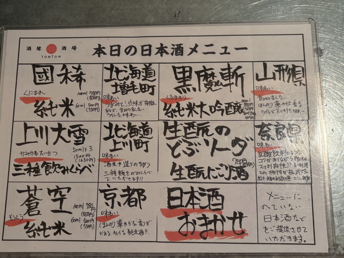居酒屋「屯屯(TONTON)」の手書き日本酒メニュー。「國稀」「上川大雪」「蒼空」や「生酛のどぶソーダ」などが並ぶ。
Handwritten Japanese sake menu at izakaya TONTON featuring brands like Kunimare, Kamikawa Taisetsu, and Soku.