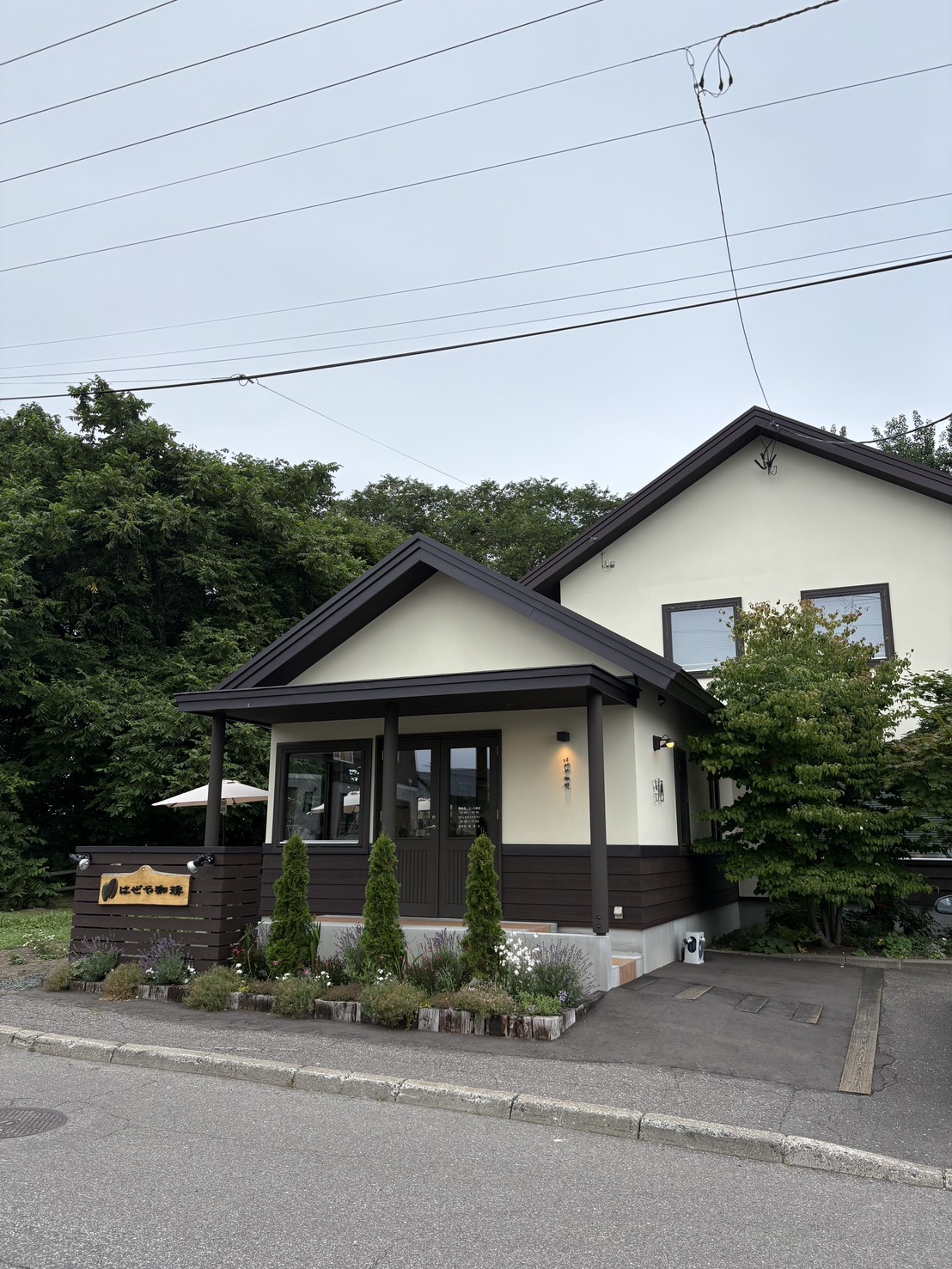 アイボリーとブラウンの外壁に緑豊かな植栽が映える、網走のエスプレッソ・珈琲焙煎所「はぜや珈琲」の外観
Exterior view of Hazeya Coffee, a specialty coffee roastery in Abashiri with lush greenery and a stylish building