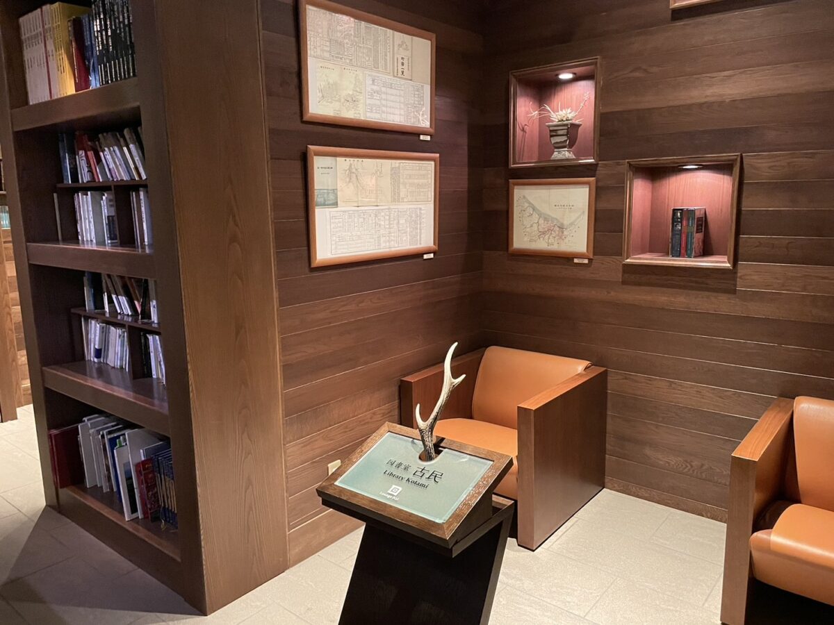 落ち着いた木目の壁面に本や資料が並ぶ、館内の図書室スペース「古民」
Library lounge "Komin" filled with books and local historical materials at Tsuruga Resort