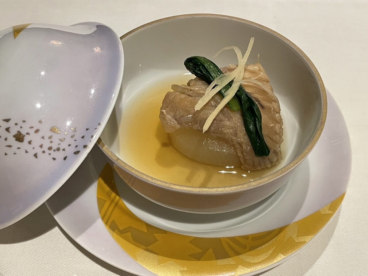 上品な出汁と大根の上に美しく盛り付けられた、職人技が光る魚の煮物料理
Expertly simmered fish dish served with daikon radish in a flavorful broth