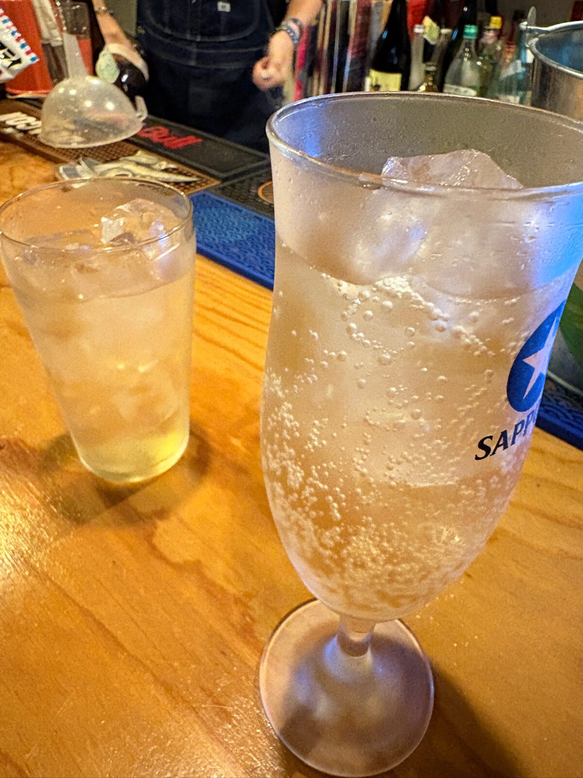 カウンター席に置かれた、炭酸の泡が涼しげなサッポロのグラスドリンク