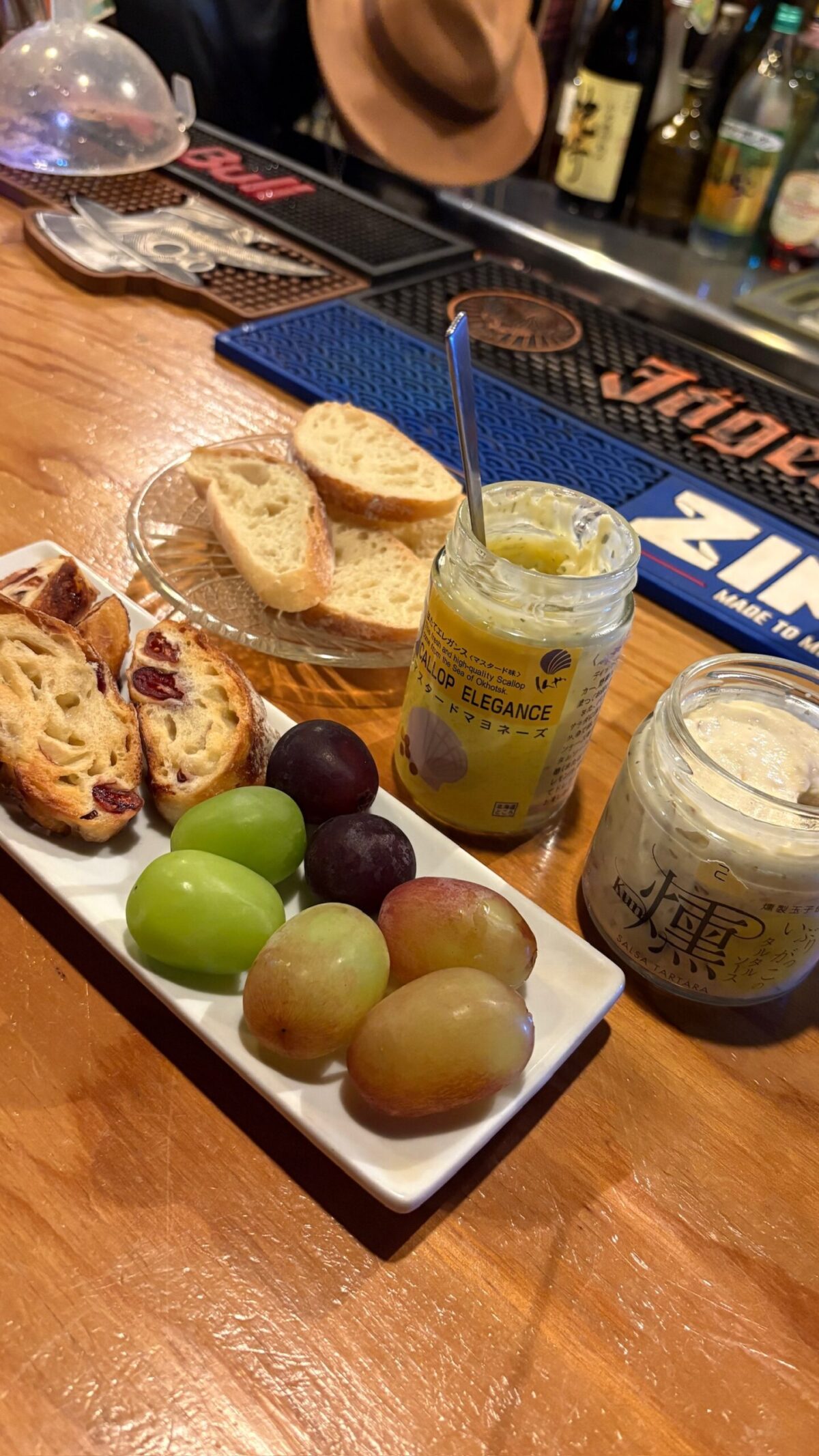 カウンターに並んだ、お酒の合間にぴったりなパン、色鮮やかなフルーツ、瓶詰めのディップ
